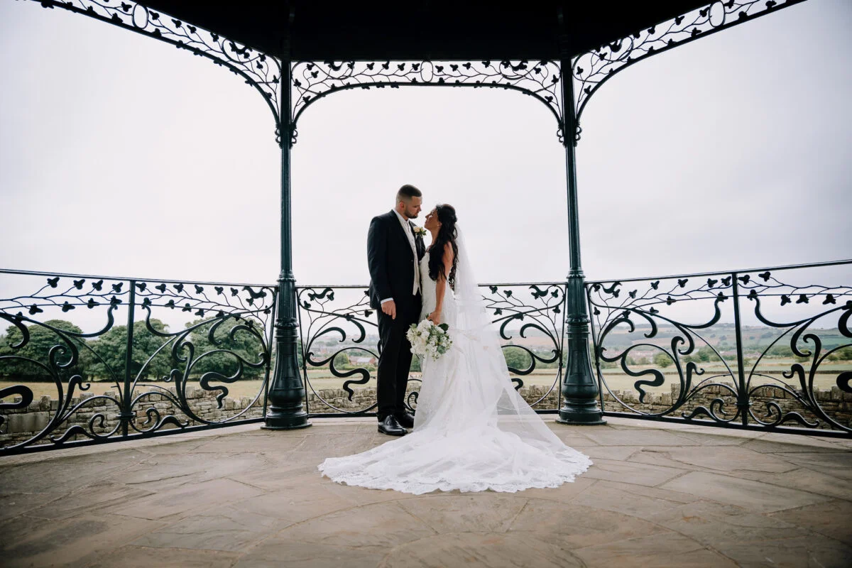 A bride and groom standing in front of an ornate gazebo.