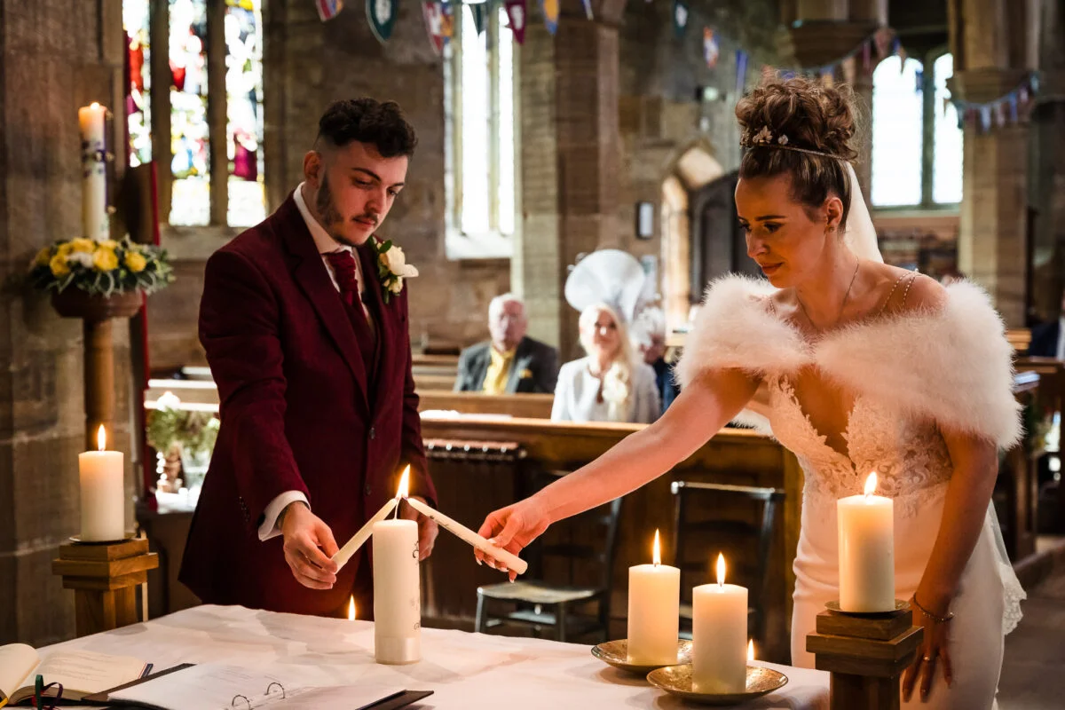 A bride and groom lighting candles in a church.