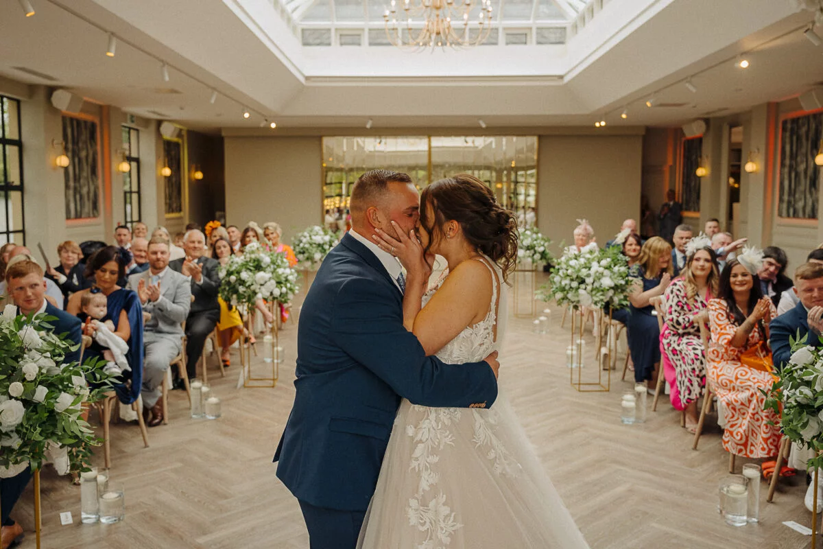 A bride and groom kiss during their wedding ceremony.
