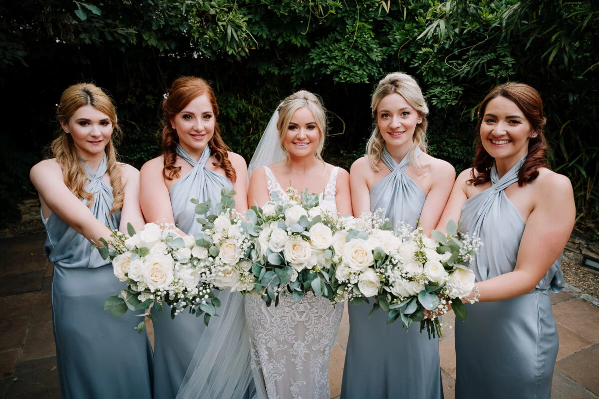 Bridesmaids holding bouquets in a garden.