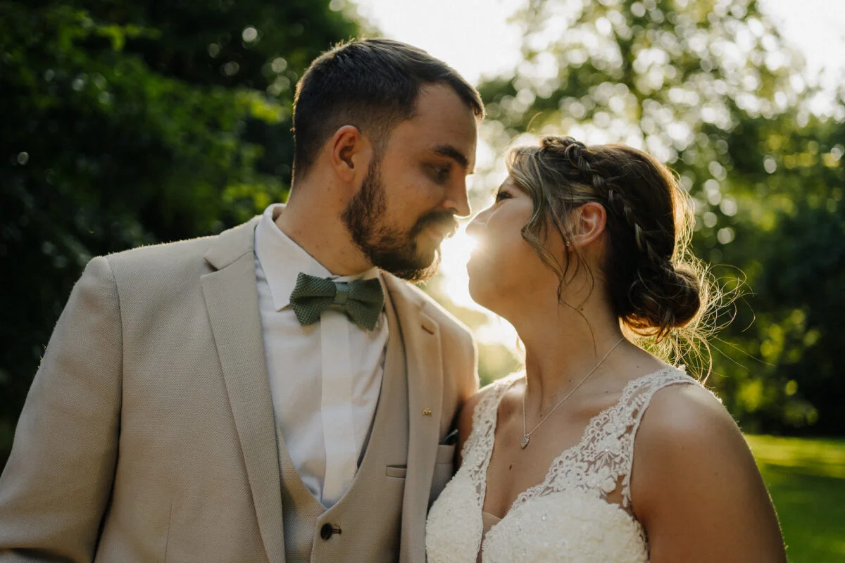 A bride and groom sharing a kiss in a park.