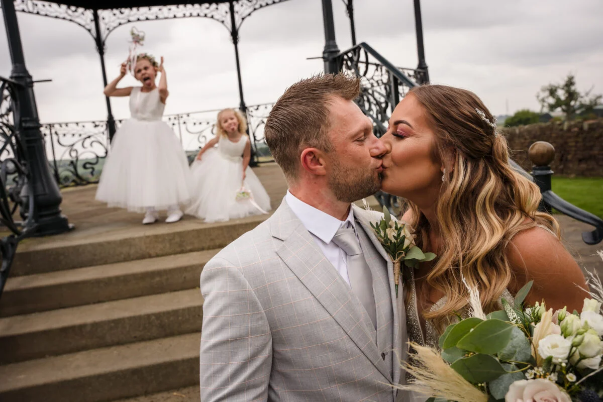 A bride and groom kissing in front of a gazebo.