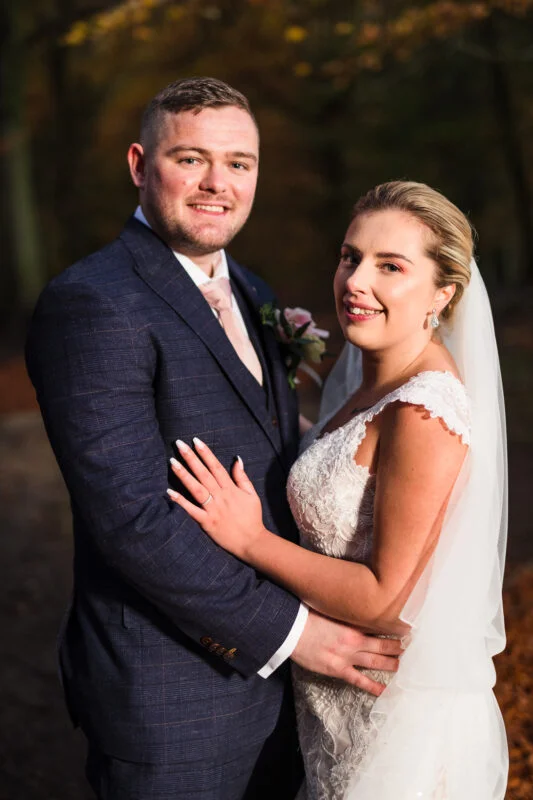 A bride and groom posing for a photo in the woods.