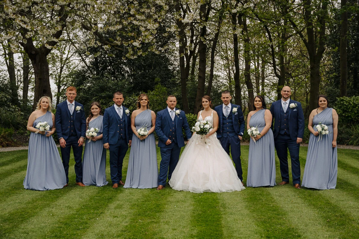 A group of bridesmaids and groomsmen posing for a photo.