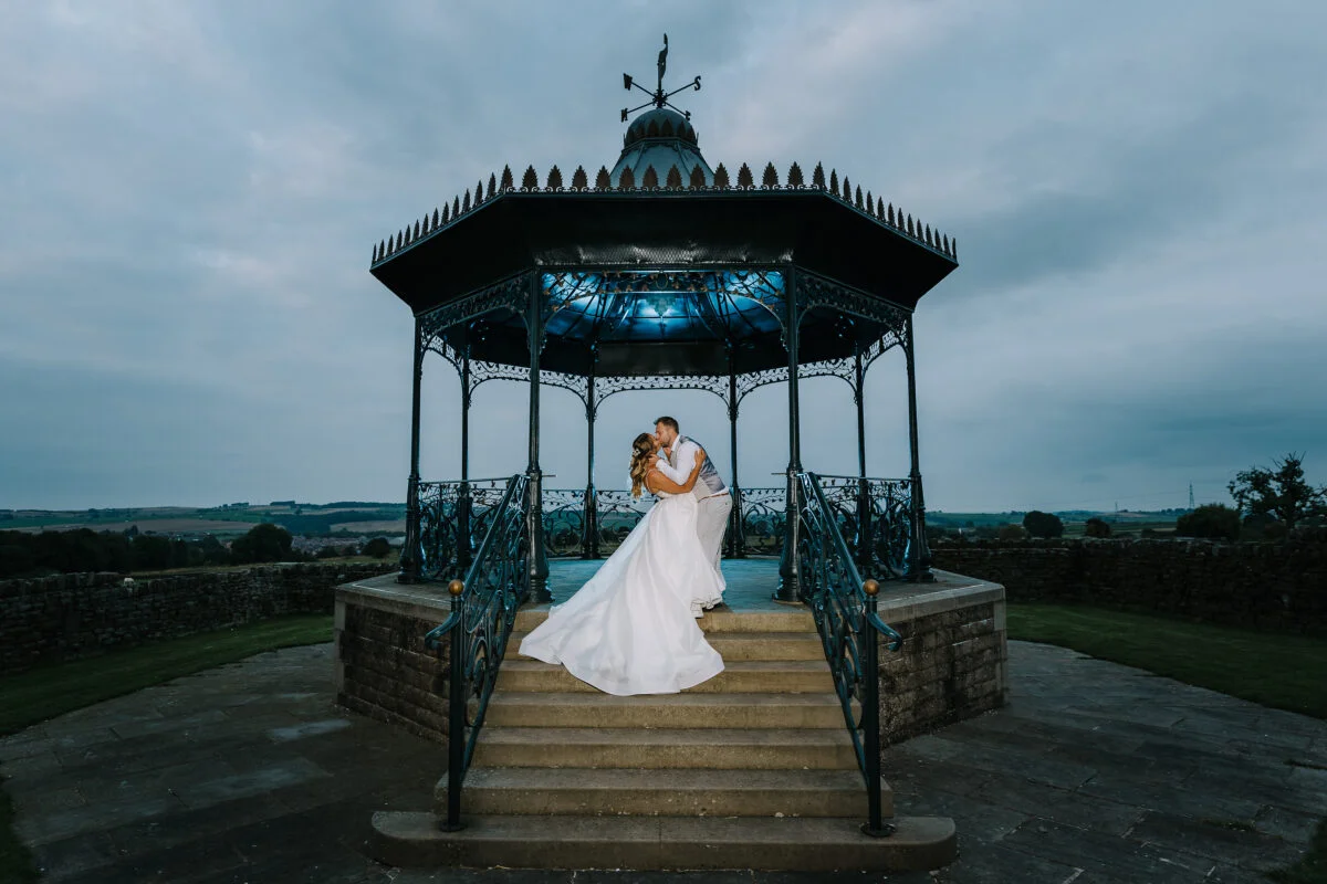 A bride and groom posing in front of a gazebo.