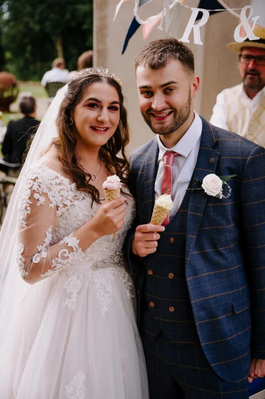 A bride and groom holding ice cream cones at their wedding.