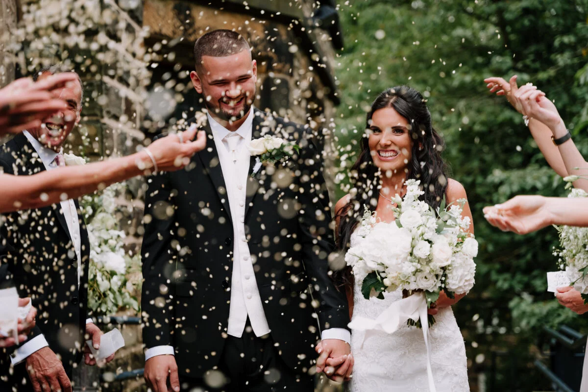 A bride and groom are being confettied at their wedding.