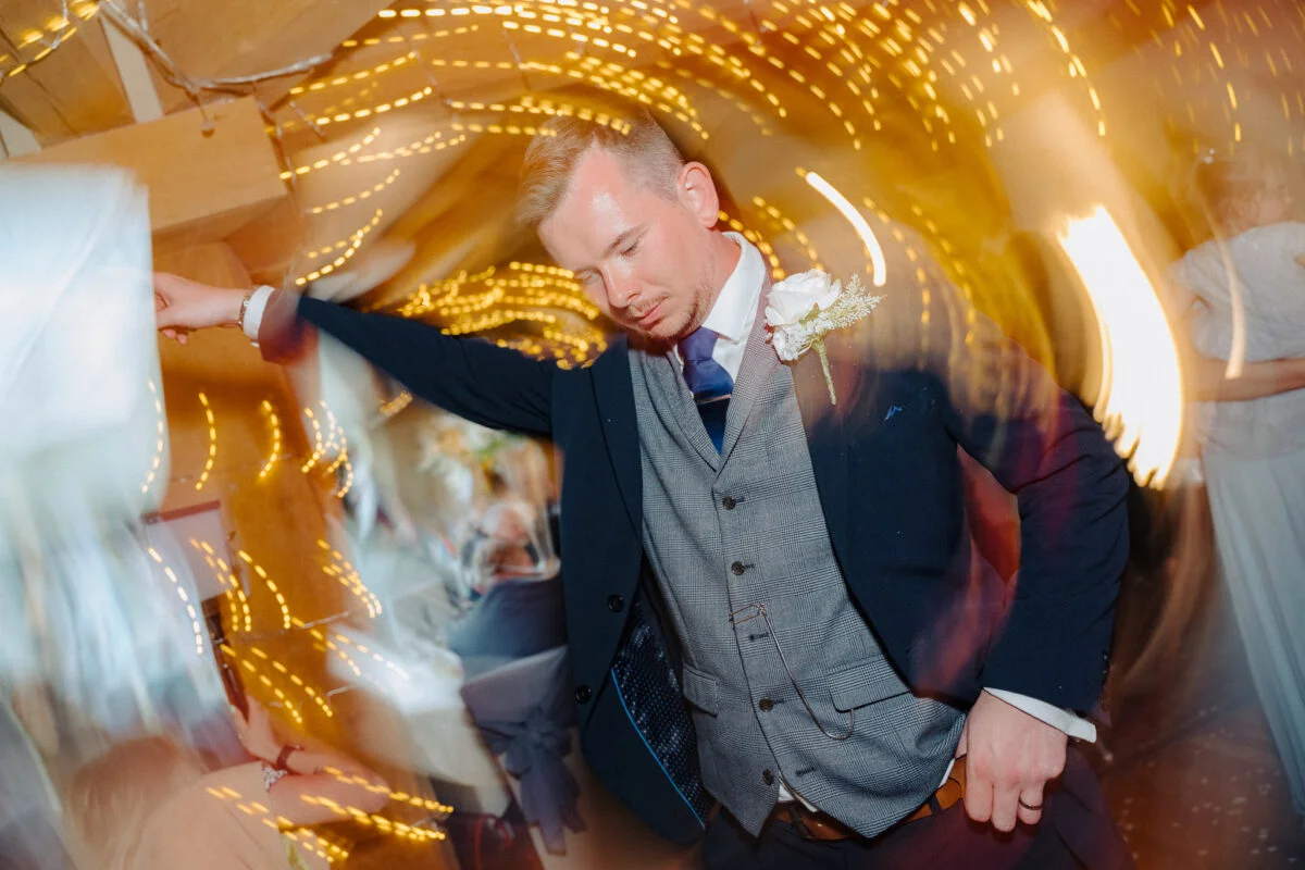A man in a suit dancing at a wedding.