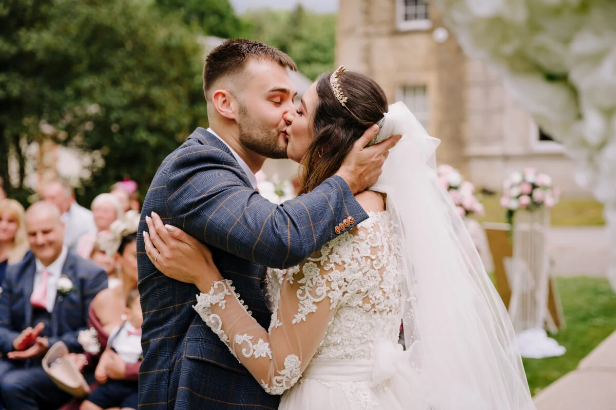 A bride and groom kiss during their wedding ceremony.