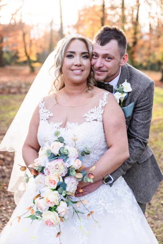 A bride and groom posing for a photo in the woods.