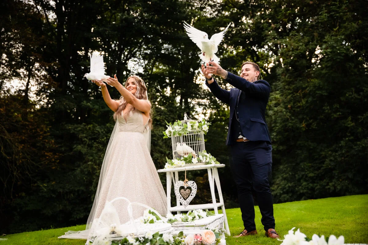 A bride and groom throwing doves at each other.