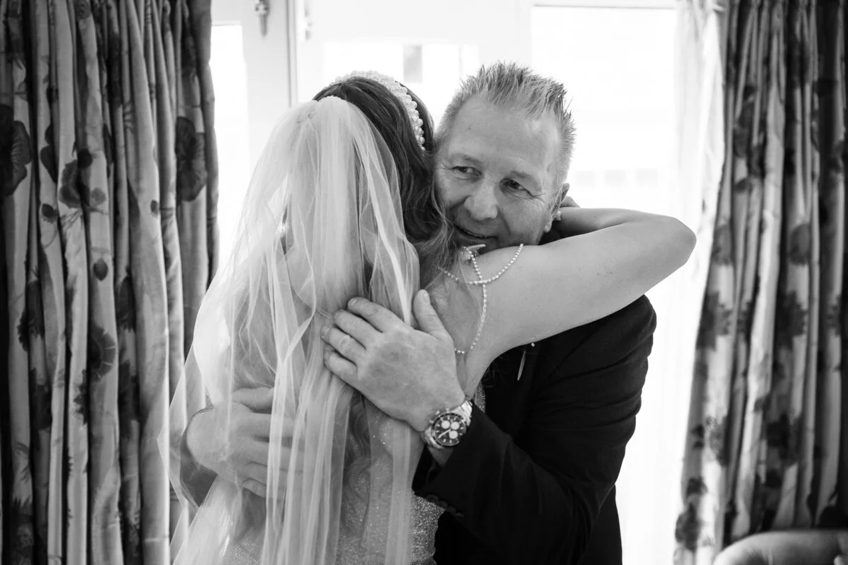 A black and white photo of a bride hugging her father.