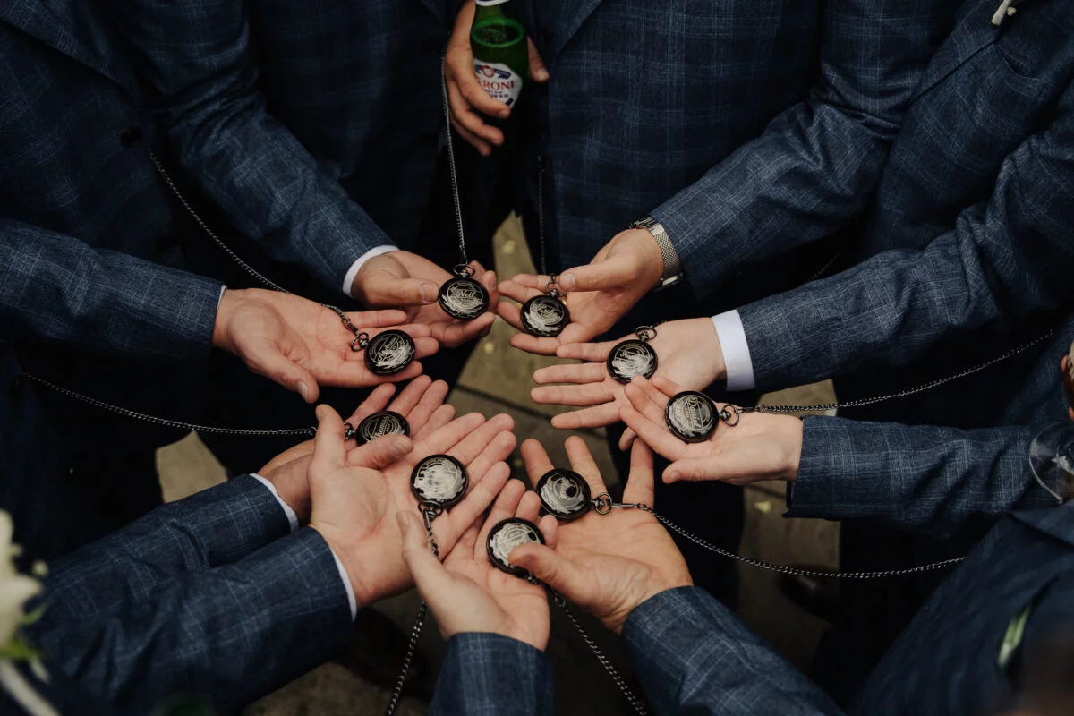 A group of groomsmen holding watches in their hands.