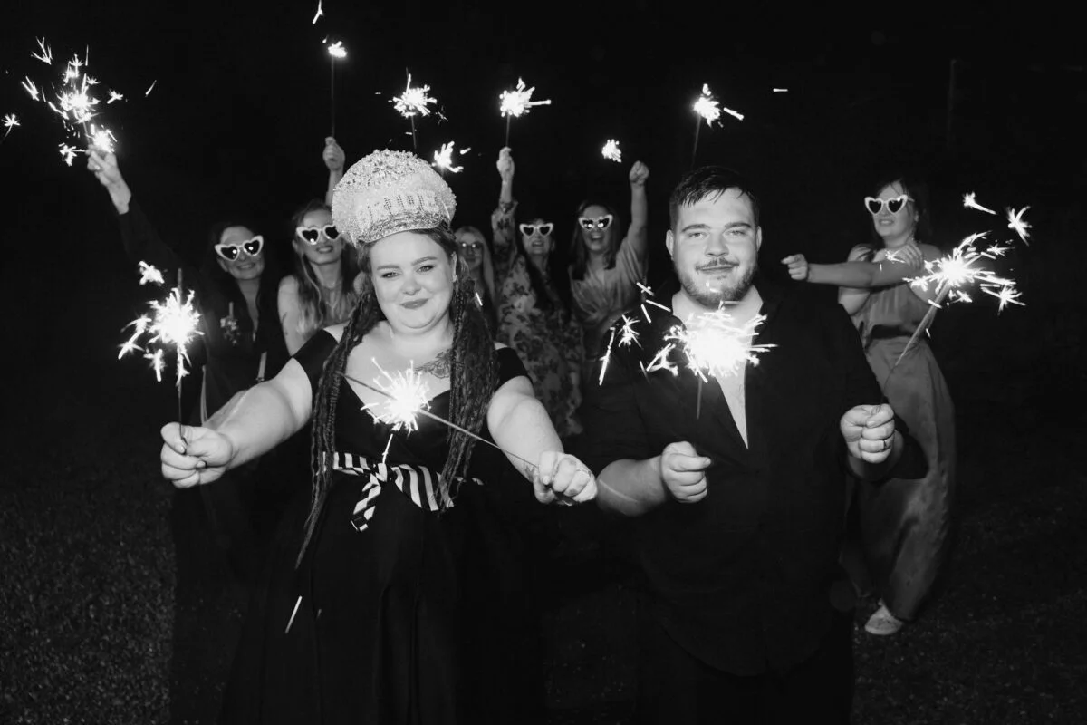 A black and white photo of a couple holding sparklers.