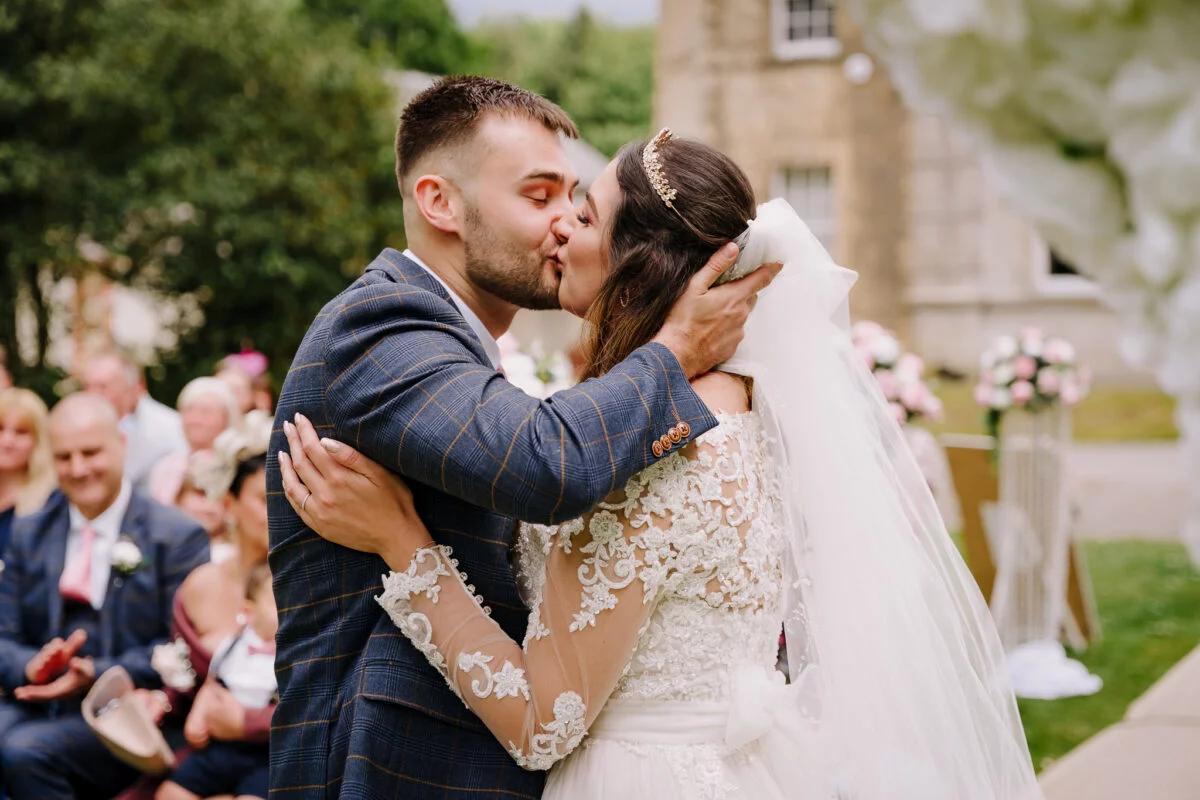 A bride and groom kiss during their wedding ceremony.