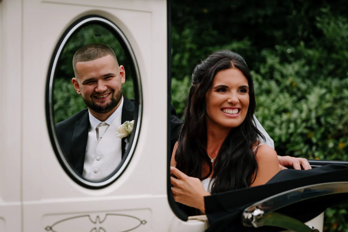A bride and groom in a horse drawn carriage.