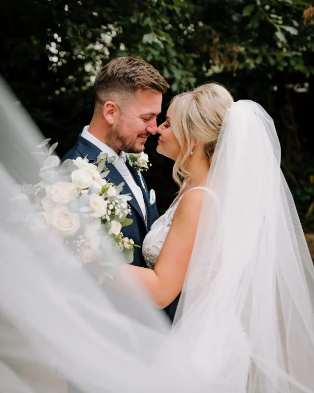 A bride and groom kissing under a veil.