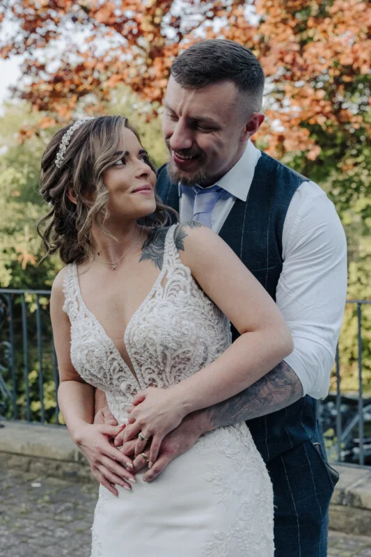 A bride and groom hugging in front of a brick wall.