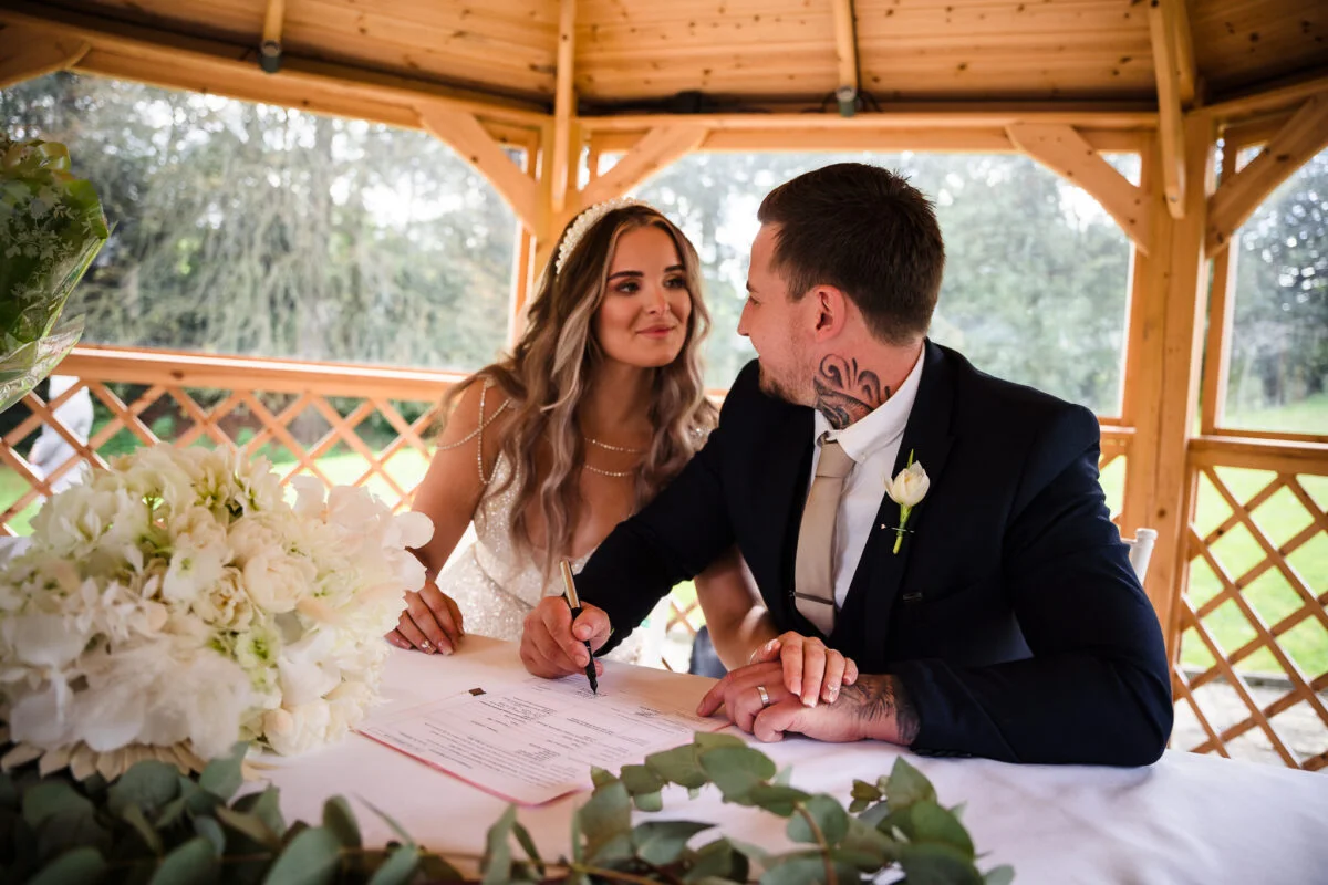 A bride and groom signing their wedding vows in a gazebo.