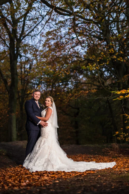 A bride and groom posing for a photo in the woods.