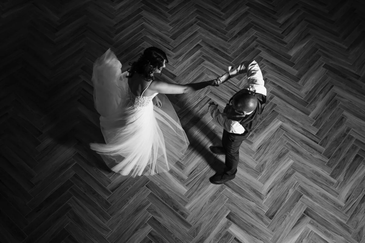 A bride and groom dancing on a wooden floor.