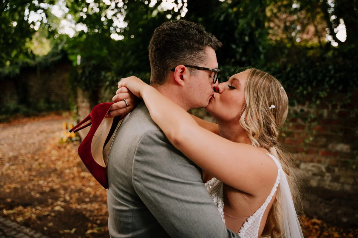 A bride and groom kissing in front of a brick wall.