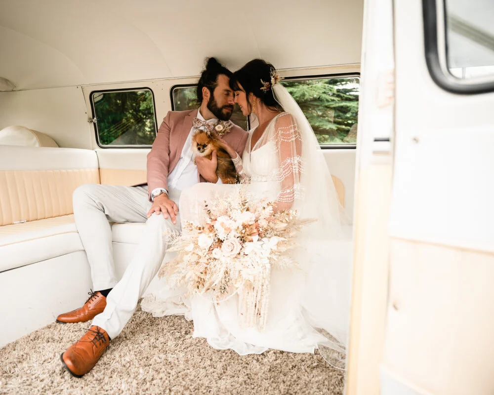 A bride and groom sitting in the back of a vw camper van.