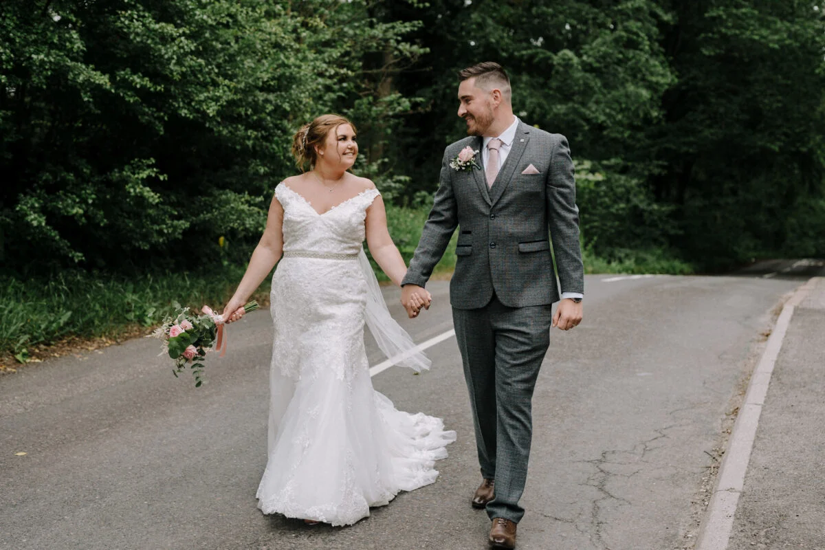 A bride and groom walking down a country road.
