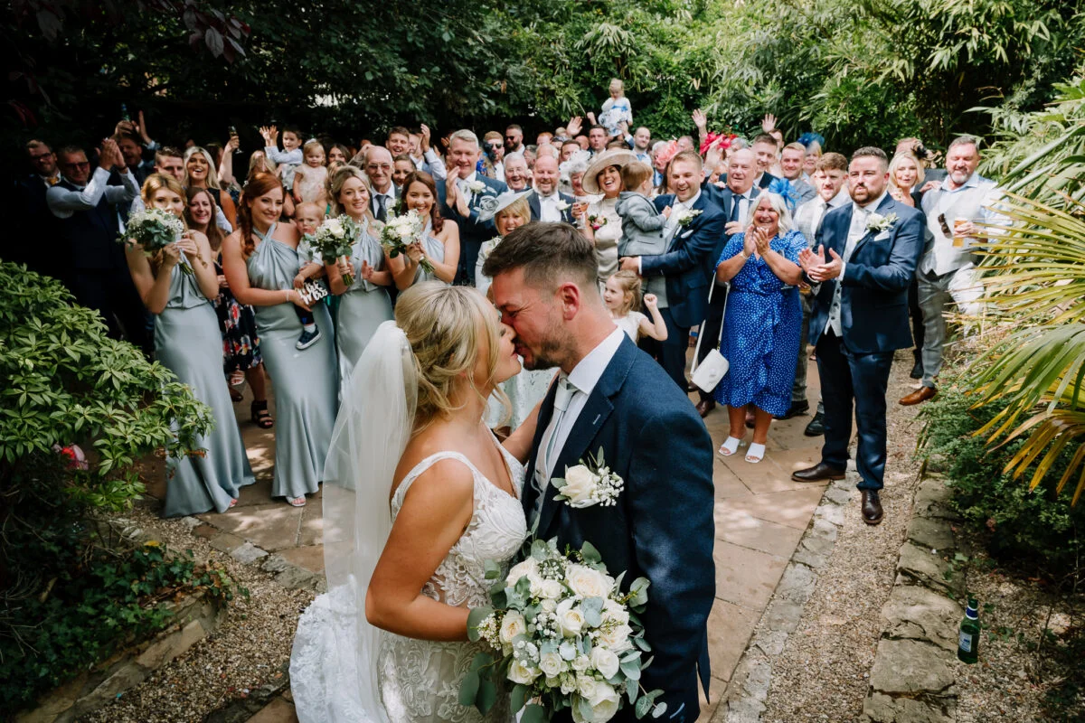 A bride and groom kissing in front of a crowd of people.