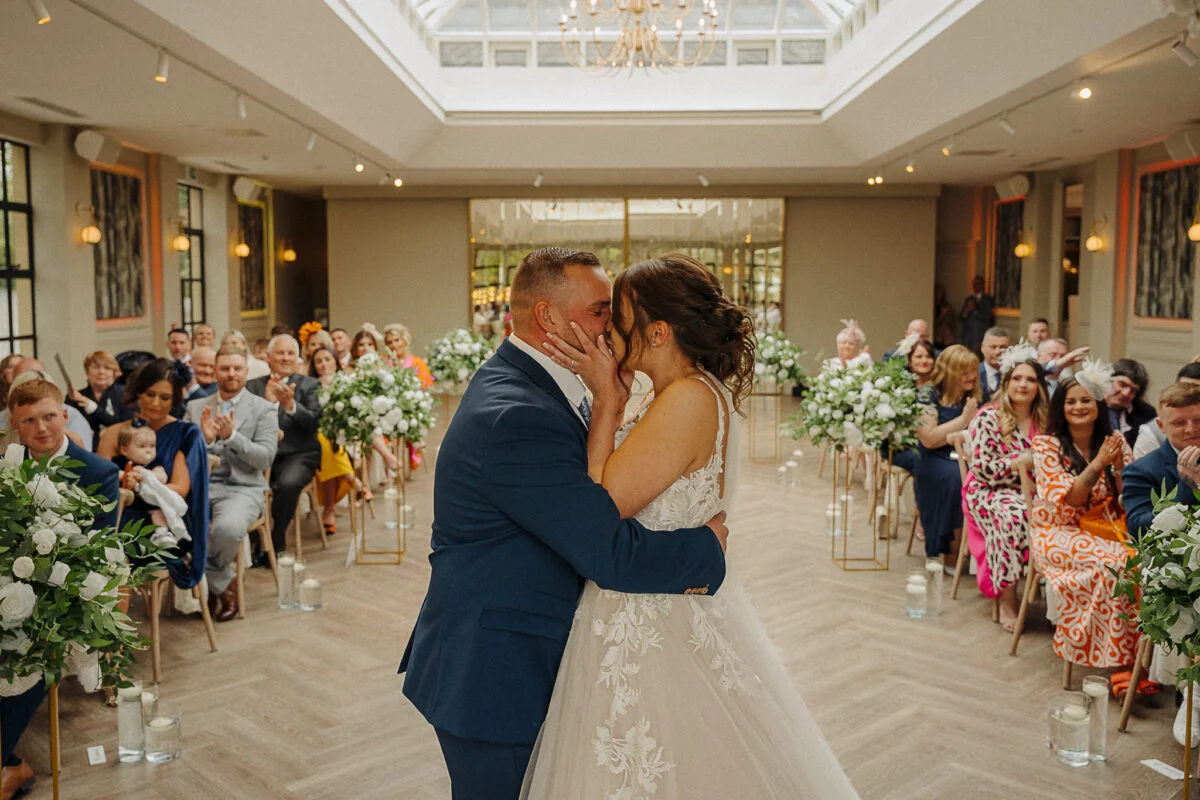 A bride and groom kiss during their wedding ceremony.