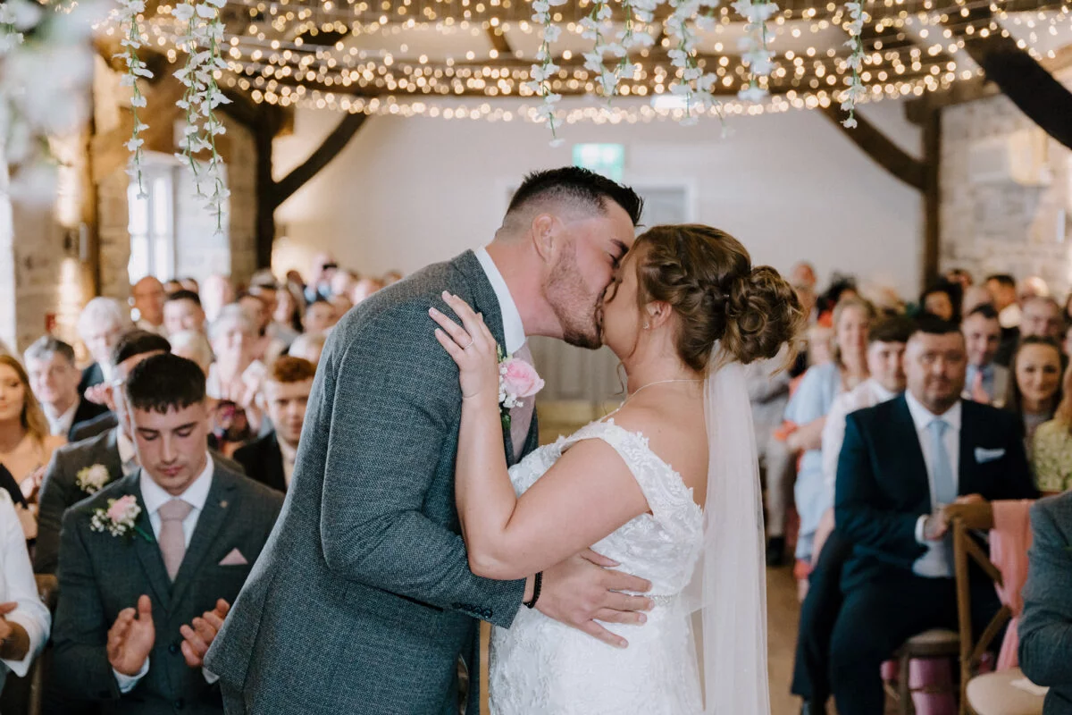 A bride and groom kiss during their wedding ceremony.