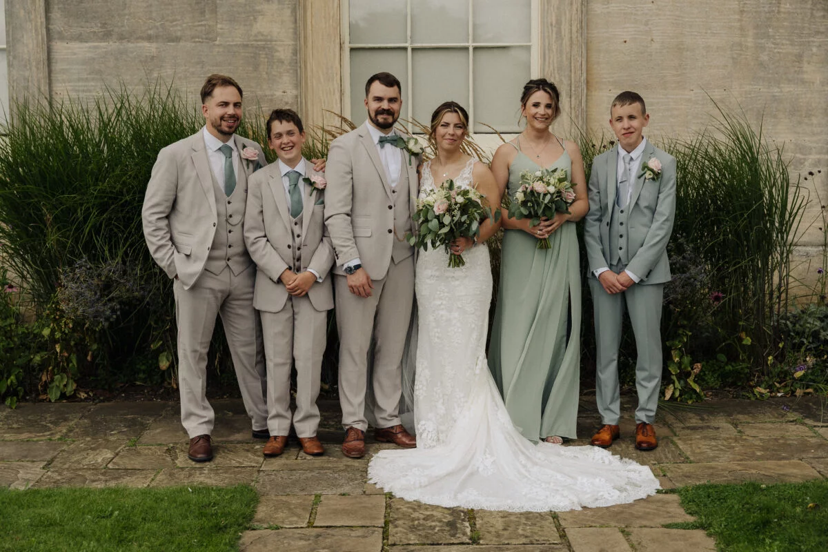 A group of bridesmaids and groomsmen posing in front of a building.