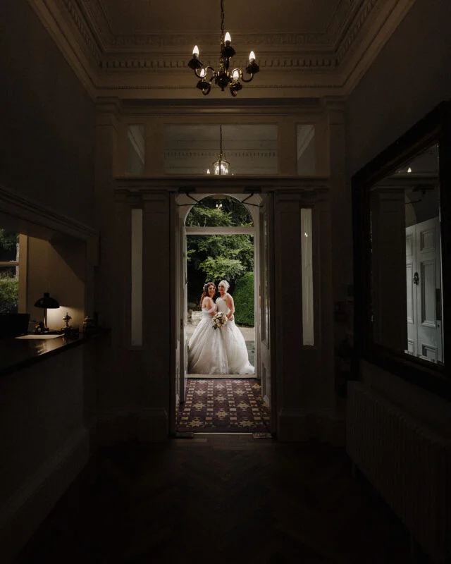Two brides standing in a doorway.