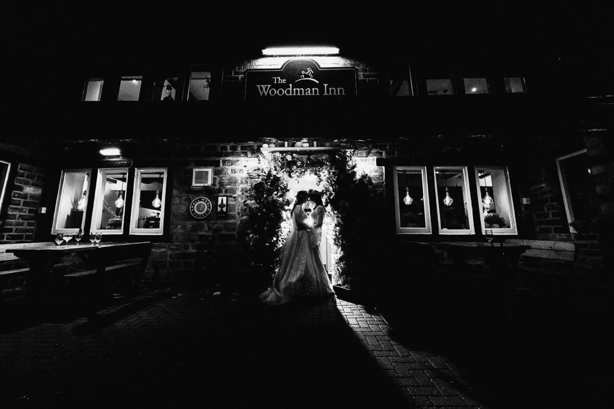 A bride and groom standing in front of a restaurant at night.