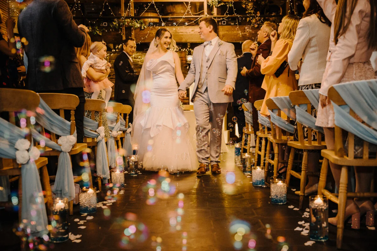 A bride and groom walking down the aisle with bubbles.