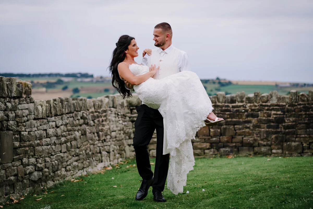 A bride and groom holding each other in front of a stone wall.