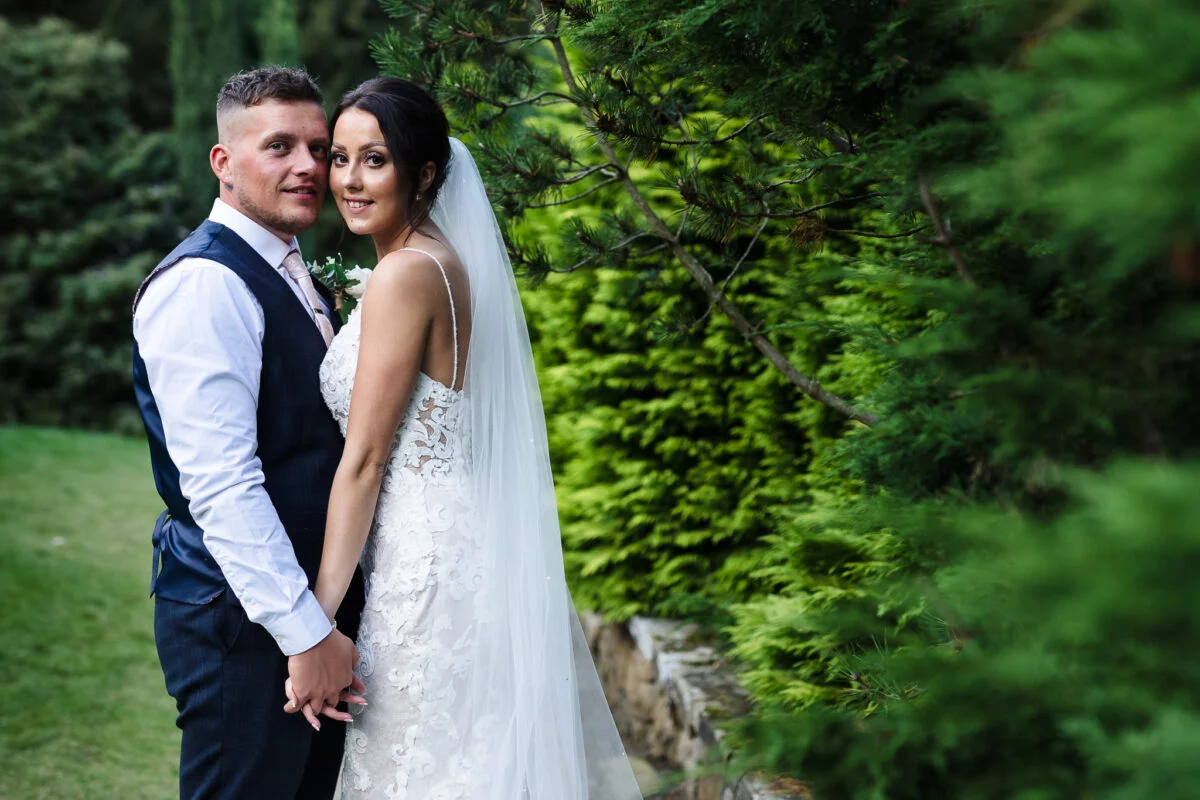 A bride and groom posing for a photo in a garden.