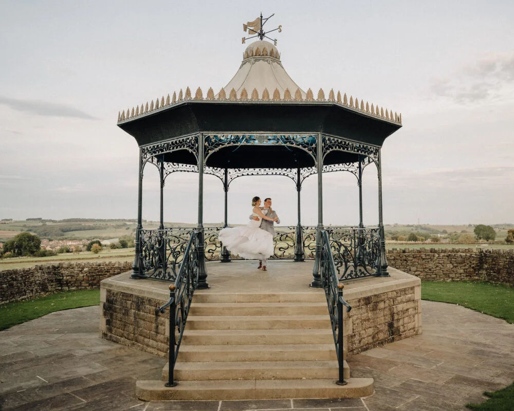 A bride and groom standing in front of a gazebo.