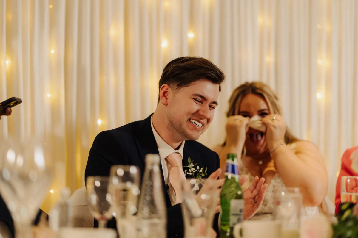 A bride and groom laughing at their wedding reception.