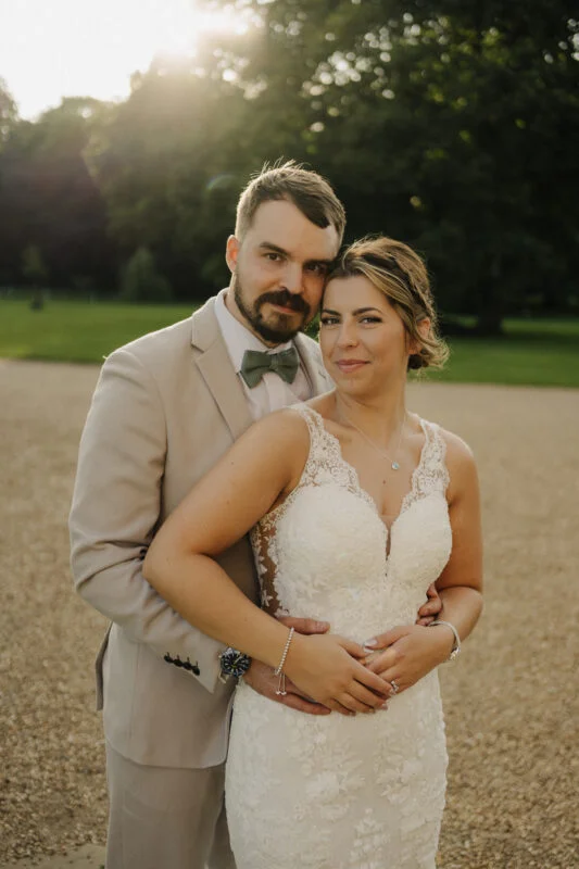 A bride and groom posing for a photo in a park.