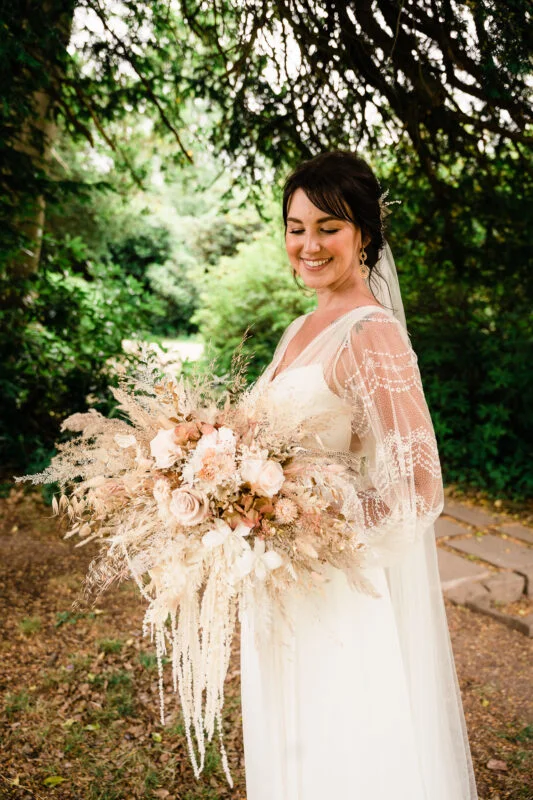 A bride holding her wedding bouquet in the woods.