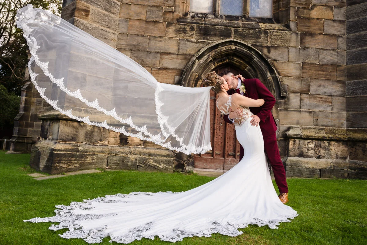A bride and groom kissing in front of a church.