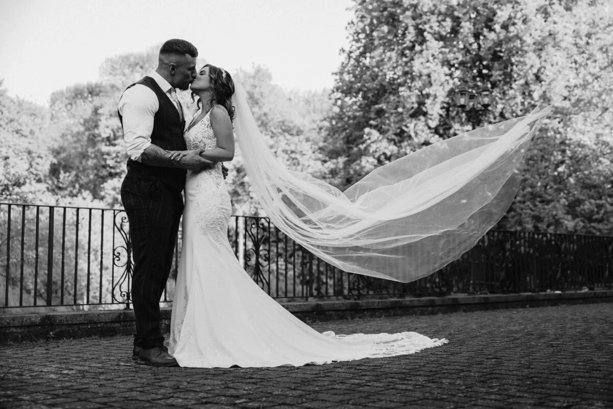 Black and white photo of a bride and groom kissing.