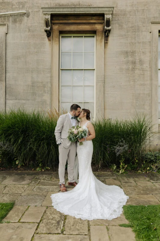 A bride and groom kissing in front of a large building.