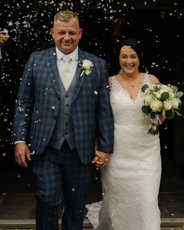 A bride and groom with confetti thrown at them.