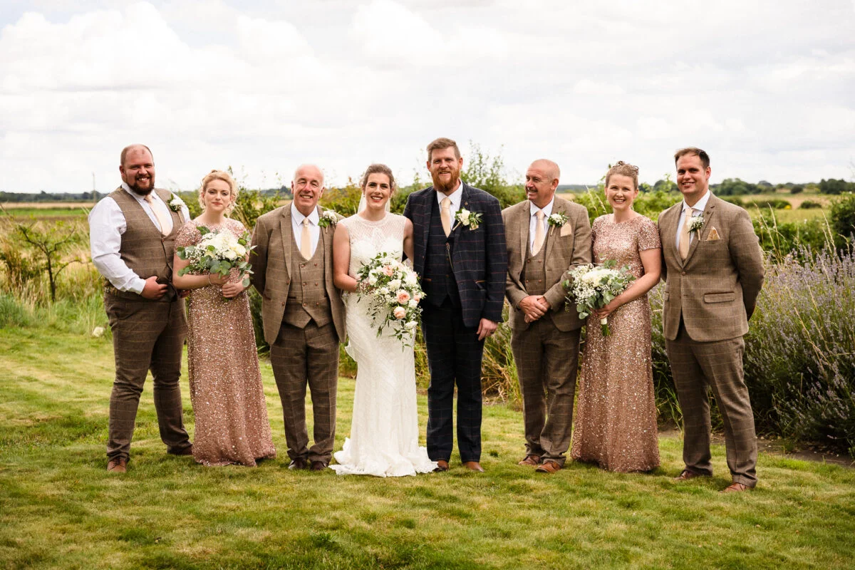 A wedding party posing for a photo in a field.