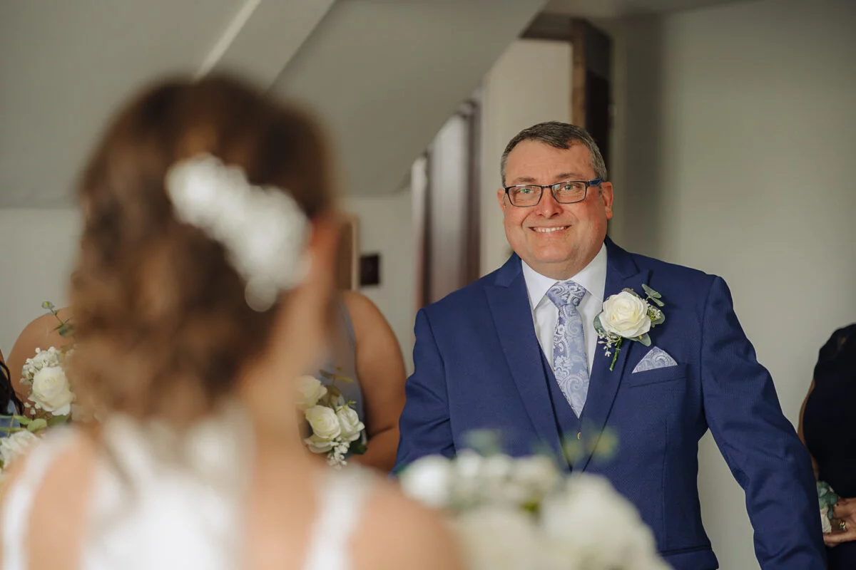 A man smiles as his bride walks down the aisle.