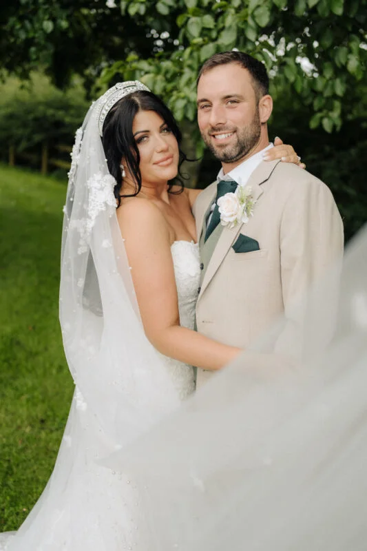 A bride and groom posing for a photo in a field.
