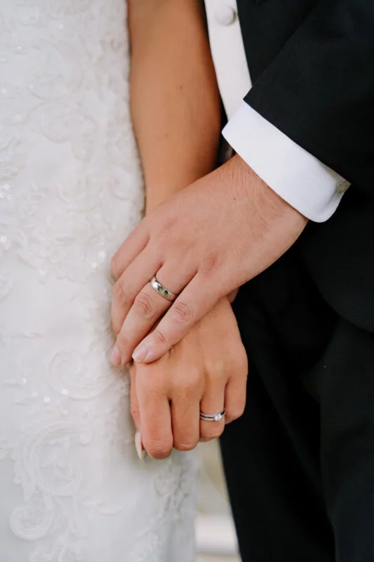 A bride and groom holding their wedding rings.