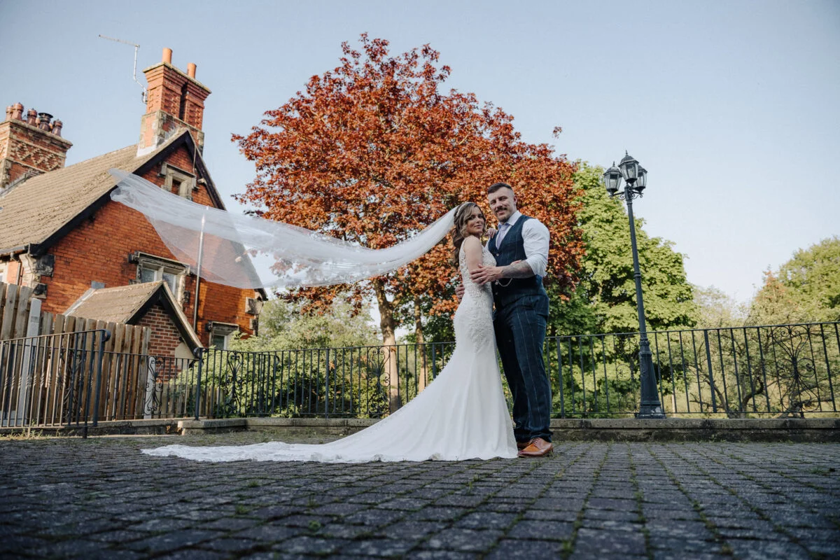 A bride and groom posing in front of a house.